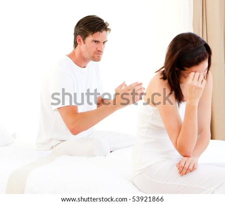 Stressed couple having an argument sitting on their bed