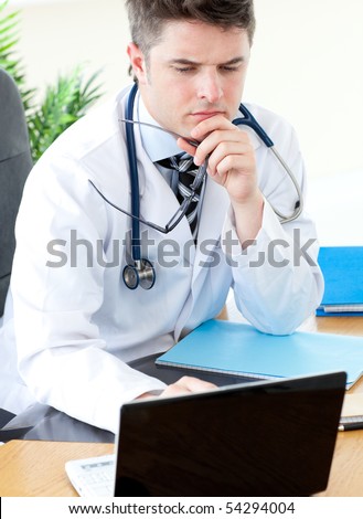 Worried male doctor using a laptop in his practice