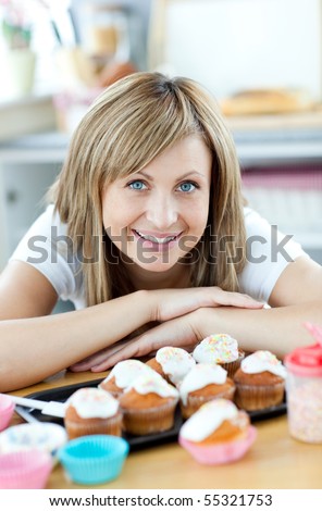 Delighted woman eating cakes in the kitchen at home