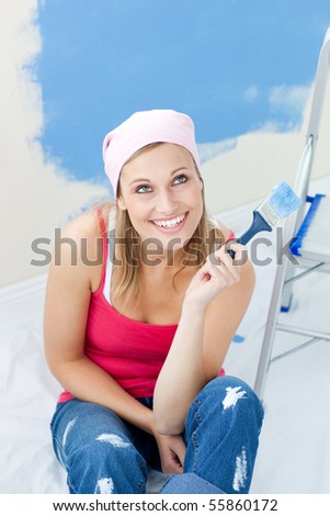 Cheerful woman  painting a room in her new house