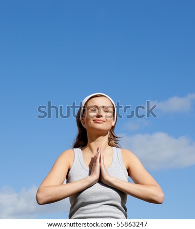 Portrait of a radiant woman meditating against a blue sky