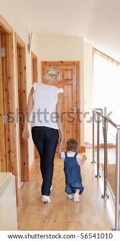 Mother walking with her daughter on the floor upstairs besides the staircase