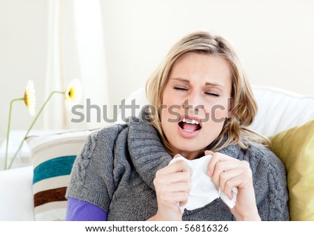 Young woman sneezes on a sofa