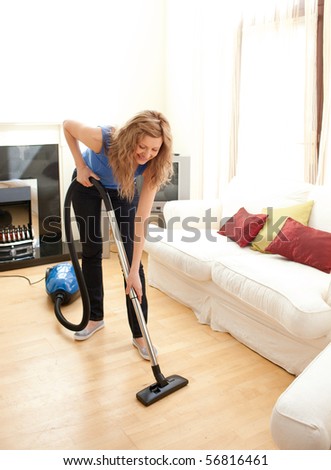 Happy woman cleaning her living room with a vacuum cleaner