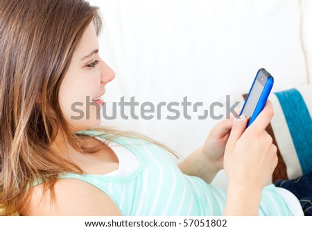 Delighted woman writing a text message with her mobile phone