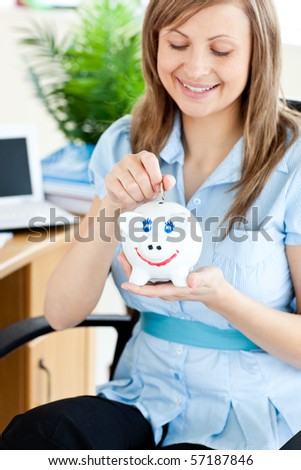 Delighted woman sitting in office on a chair with a piggy bank in her hand