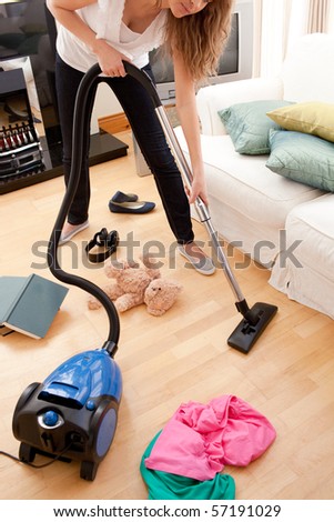 Blond young woman cleaning the living-room with a vacuum cleaner