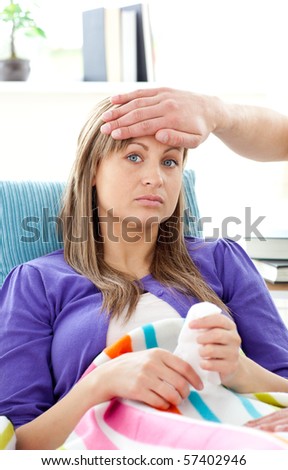 Depressed woman lying on a sofa man feel her temperature in the living room