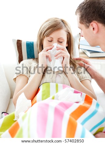 Ill woman with tissue lying on  a sofa with her boyfriend