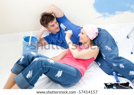 Charming couple relaxing after painting a room in their new house