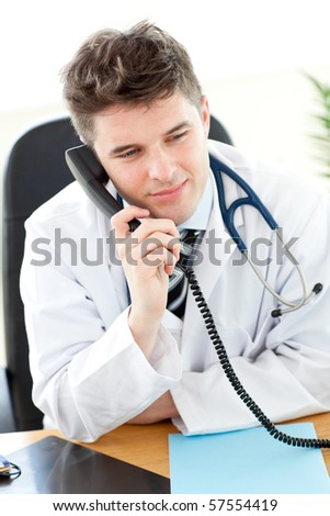 Attractive male doctor talking on the phone in his office