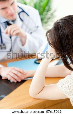 Male doctor talking with his patient holding her hand