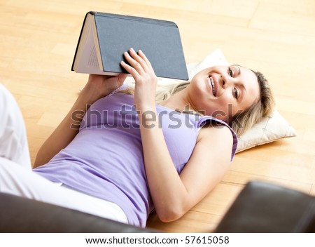 Bright woman lying on the floor holding a book