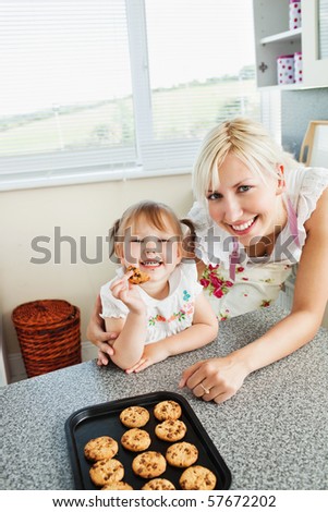 Smiling girl eating cookie in kitchen