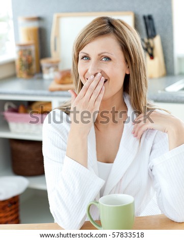 Yawning woman with a cup in the kitchen