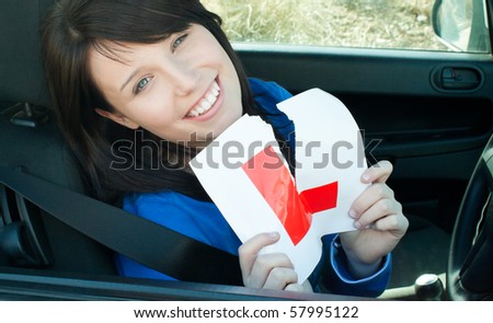 Cheerful young female driver tearing up her L sign sitting in her car