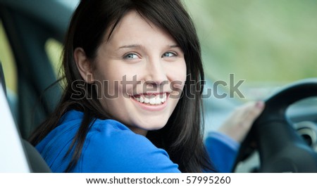 Bright female driver sitting in a car smiling at the camera