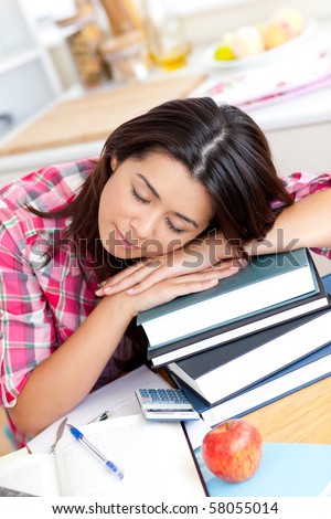 Tired asian student sleeping on her books in the kitchen