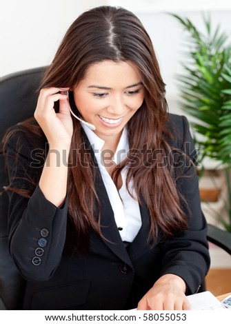 Self-assured asian businesswoman wearing headphones siiting at her disk in the office