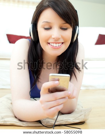 Charming young woman listen to music lying on the floor in the living room
