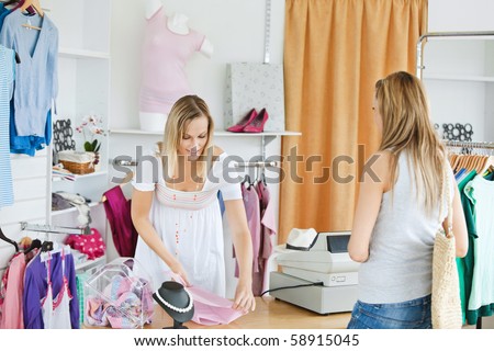 Friendly saleswoman packing clothes in a bag  in a clothes store