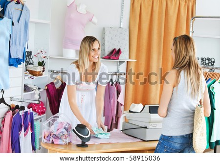 Attractive saleswoman packing clothes in a bag  in a clothes store