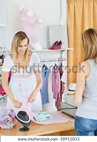 Positive saleswoman packing clothes in a bag in a clothes store