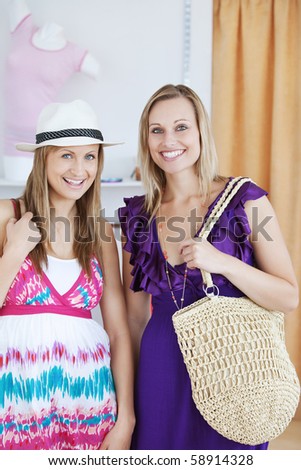 Charming female friends smiling at the camera in a clothes store