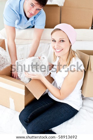 Animated young couple packing a box at home