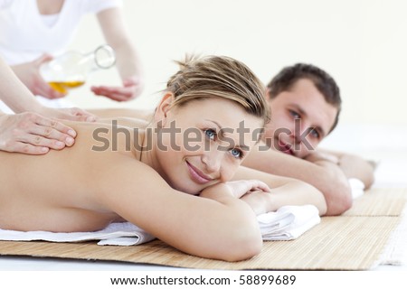 Happy young couple enjoying a back massage with oil in a health spa