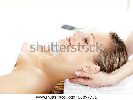 Glowing young woman  enjoying a massage in a spa center