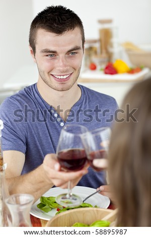 Handsome young man having dinenr with his girlfriend drinking wine at home