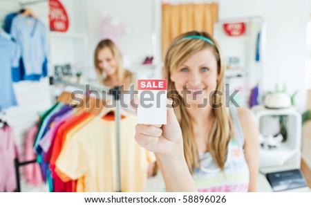 Radiant young woman holding a sale paper into the camera in a clothes store