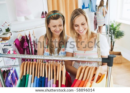 Bright young women choosing colorful shirts together in a clothes store