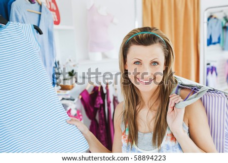 Close-up of a smiling woman doing shopping looking at the camera in a clothes store
