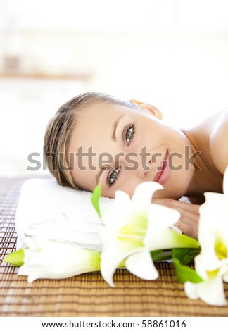 Portrait of a charming woman lying on a massage table smiling at the camera in a health spa