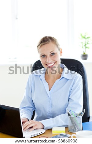 Sophisticated caucasian businesswoman using her laptop smiling at the camera in the office