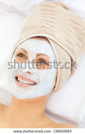 Glowing caucasian woman with white cream on her face in a spa center