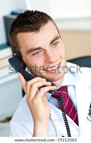 Happy male doctor talking on phone sitting in his office