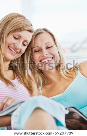 Laughing friends reading a book at home