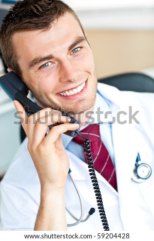 young handsome doctor on phone in his office smiling at the camera