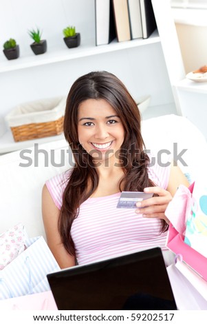 Animated asian woman holding a card smiling at the camera sitting on a sofa at home
