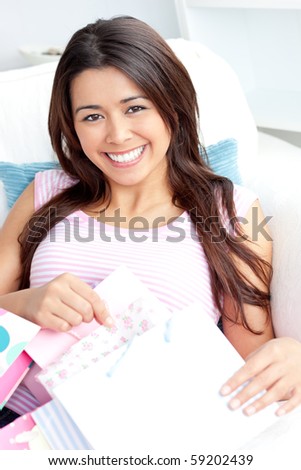 Happy asian woman with shopping bags smiling at the camera sitting on the sofa in the living-room