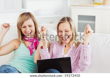 Enthusiastic friends with arms up looking at the laptop at home