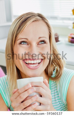 Laughing woman holding a cup of coffee at home in the kitchen