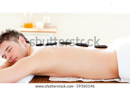 Relaxed man having  hot stone on his back in a spa center