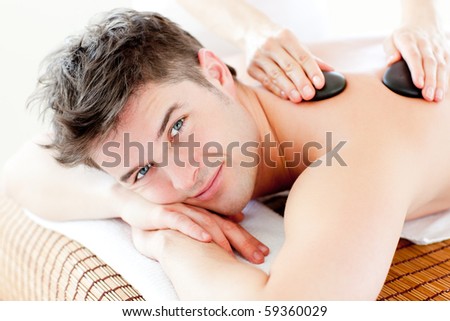 Handsome man receiving a back massage with hot stone in a spa center
