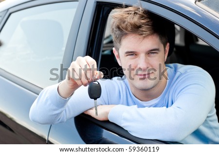 Charming young man holding a car sitting in his car smiling at the camera