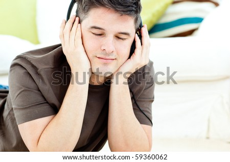 Relaxed man listen to music lying on the floor in the living-room
