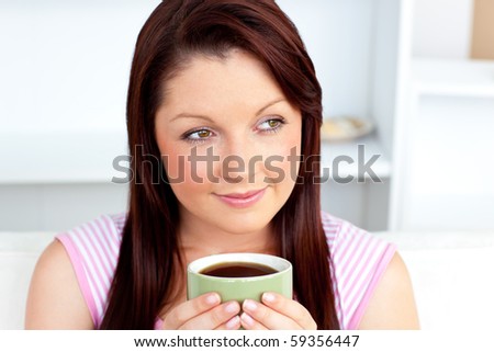 Caucasian woman holding a cup of coffee at home in the living-room